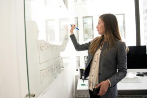 Woman writing on a dry-erase board.